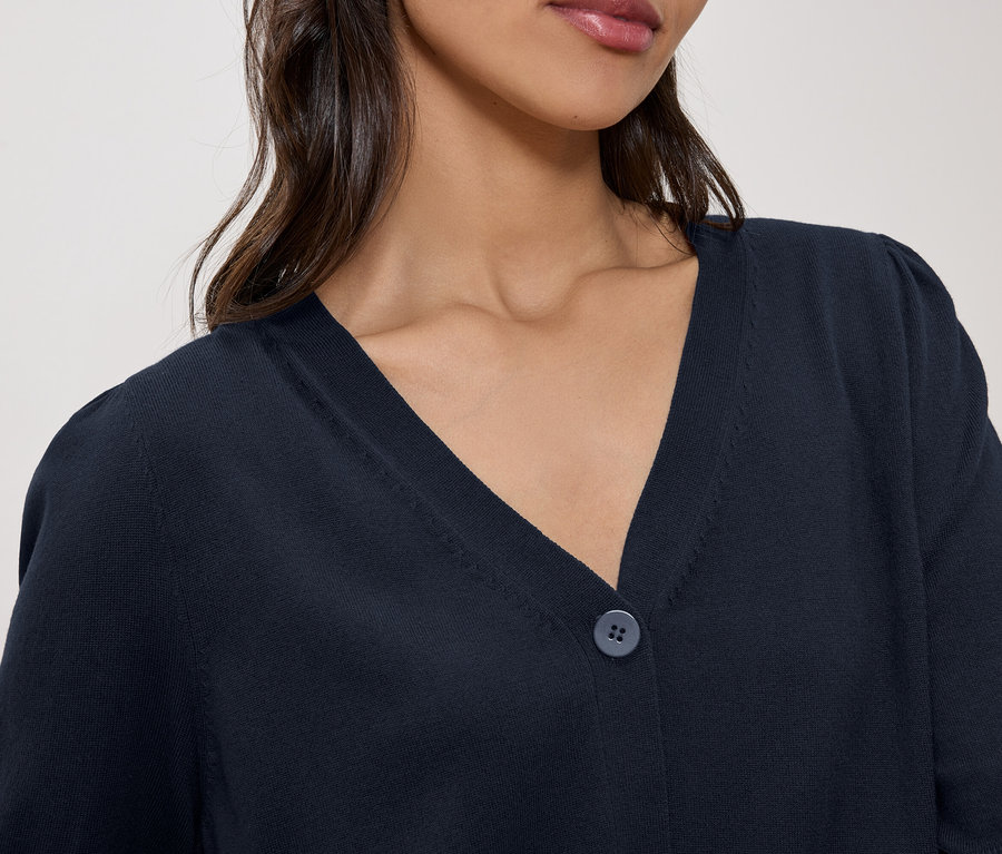 Nahaufnahme einer Frau, die eine marineblaue Strickjacke mit V-Ausschnitt und Knopf trägt.