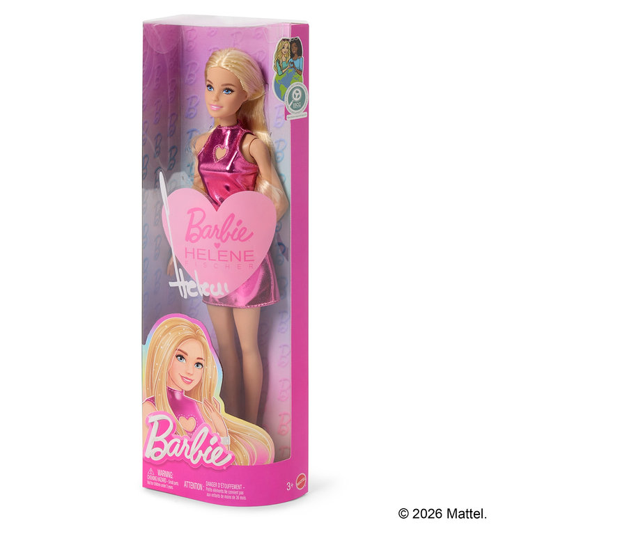 Eine blonde Barbie-Puppe in einer durchsichtigen Plastikverpackung, die ein glänzendes pinkfarbenes Metallic-Kleid trägt und ein herzförmiges Schild mit der Aufschrift „Barbie Helene Fischer“ hält.