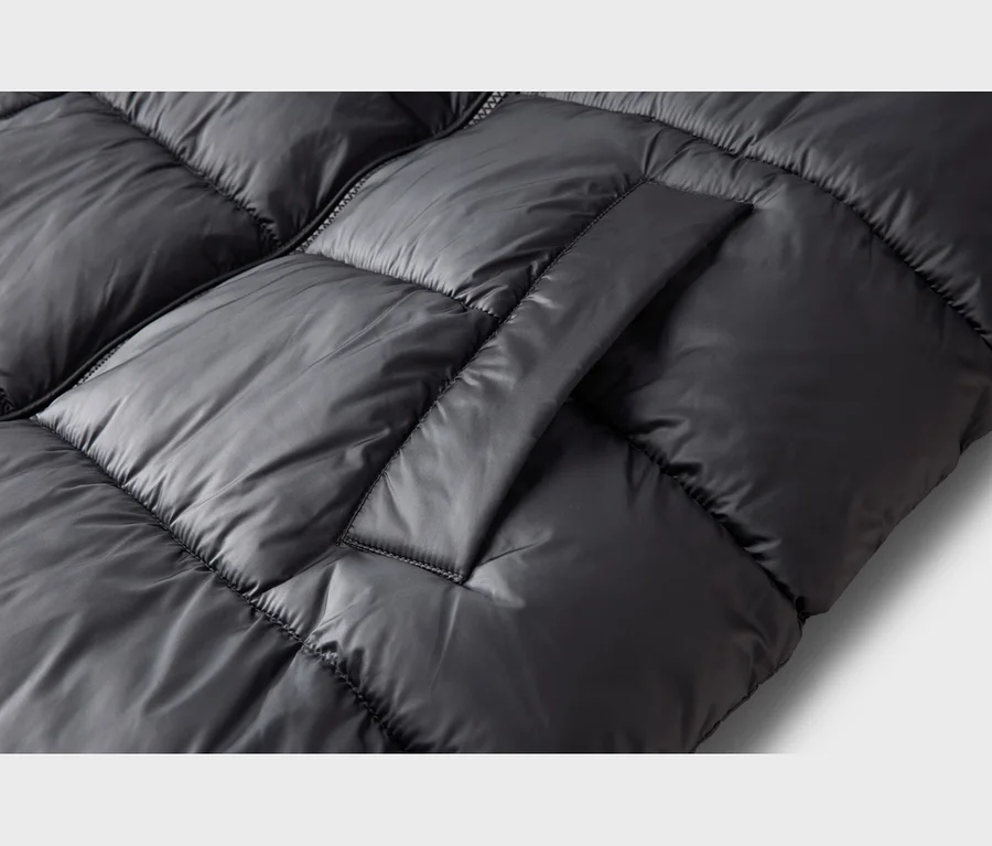 Detailansicht einer schwarzen Steppjacke mit glänzender Oberfläche, Reißverschluss und einer aufgesetzten Patte.