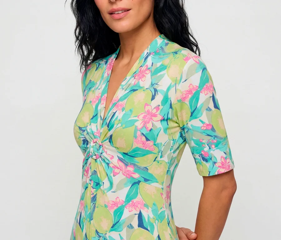 Frau trägt ein Olsen Jerseykleid mit buntem Obst- und Blumenmuster, V-Ausschnitt und gedrehtem Detail an der Brust.