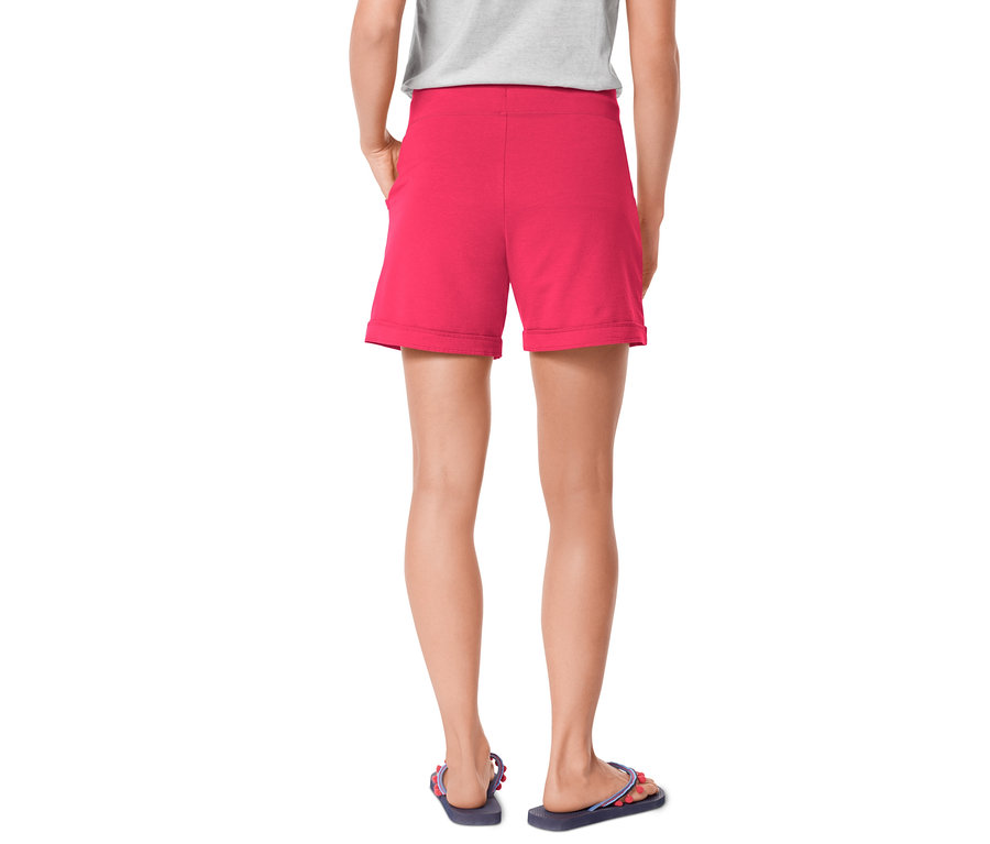 Frau von hinten trägt pinke Shorts und Zehentrenner.