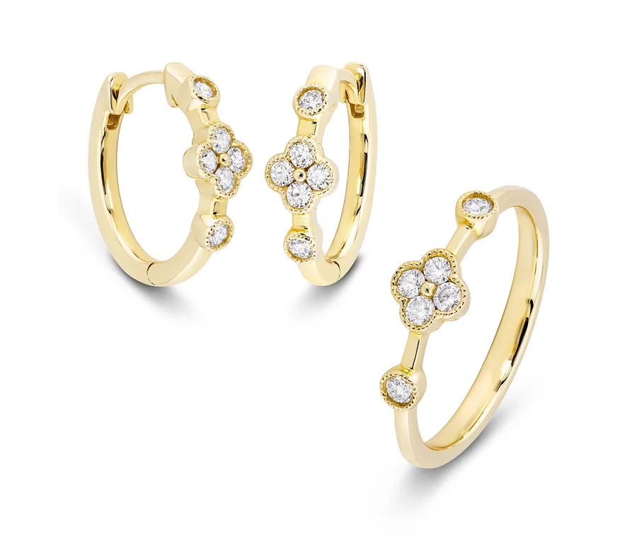 Goldene Creolen und goldener Ring mit Diamanten auf weißem Hintergrund.