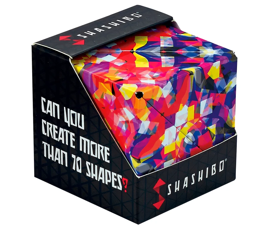 Ein farbenfroher, geometrischer Shashibo-Zauberwürfel mit einem abstrakten Muster in Rot, Gelb, Blau und Lila, präsentiert in seiner schwarzen Verpackung. Auf der Schachtel steht „CAN YOU CREATE MORE THAN 70 SHAPES?“ und „SHASHIBO“.