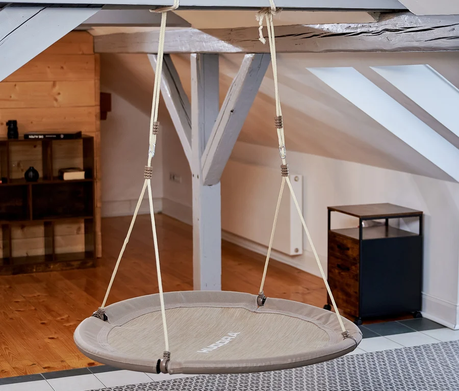 Eine beige HUDORA Nestschaukel »Lounge«, Ø 110 cm hängt von der Decke in einem Innenraum.