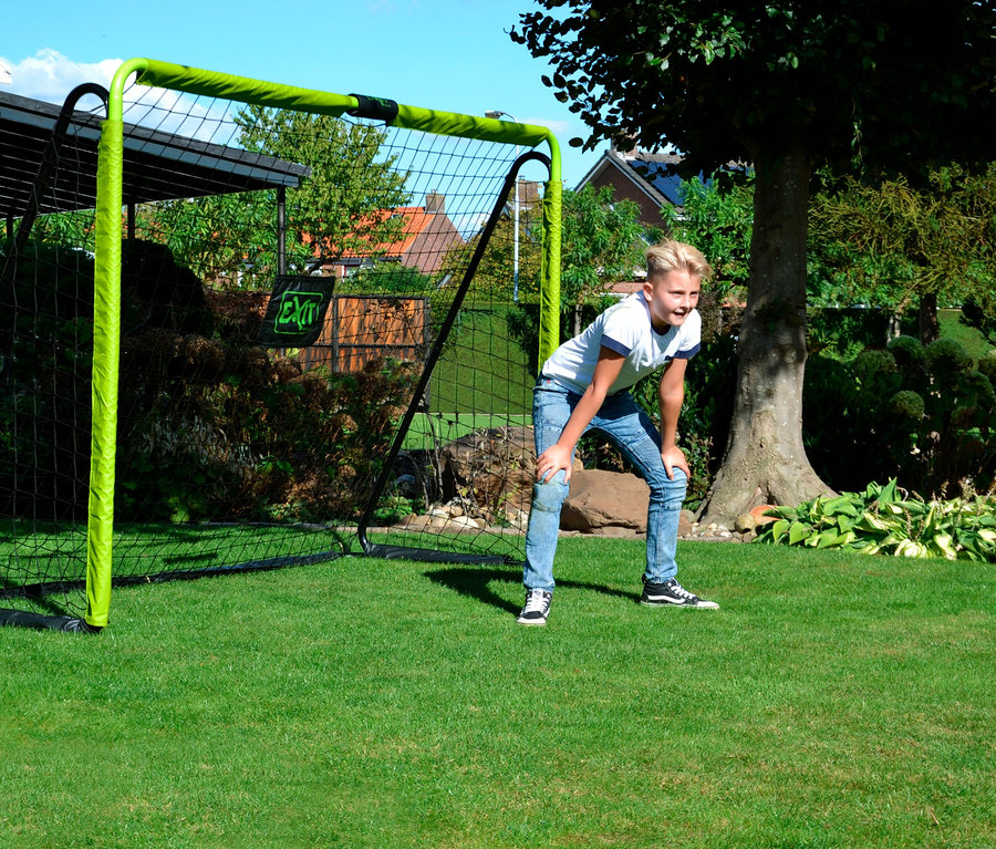 Ein Junge steht auf einem Rasen vor einem EXIT Fußballtor »Tempo 3000«.