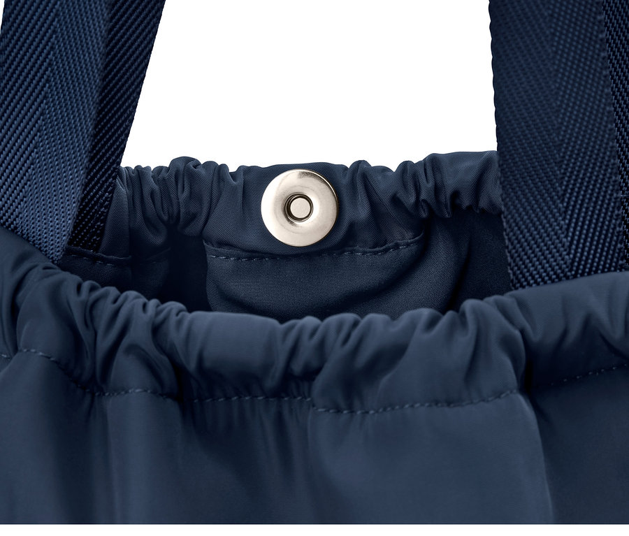 Detailaufnahme eines blauen Rucksacks mit Trägern und Kordelzug.