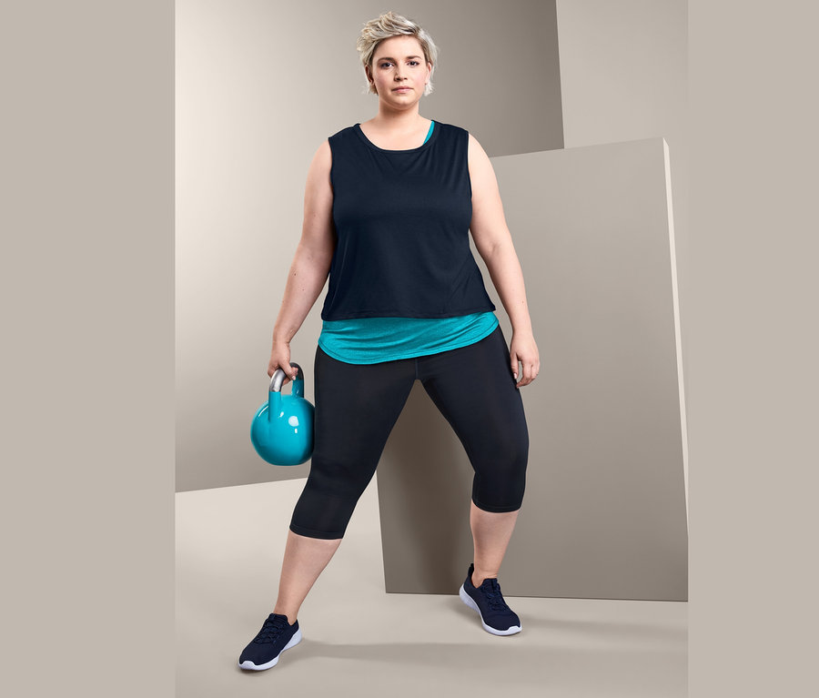 Frau hält Kettlebell und trägt ein 2-in-1-Sporttop und eine 3/4-Sporttight.
