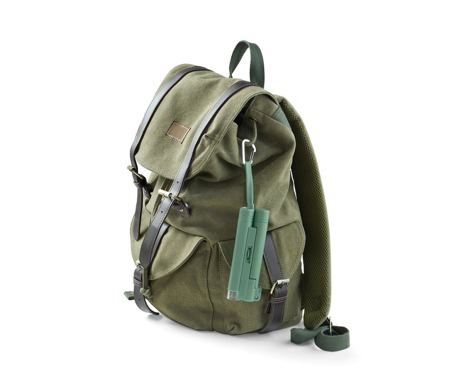 Ein grüner Rucksack mit braunen Lederriemen, an dem ein Blätter-Mikroskop hängt.