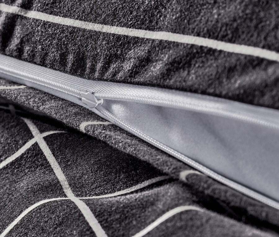 Detailaufnahme von anthrazitfarbener Biber-Bettwäsche mit Reißverschluss und weißem geometrischen Muster.