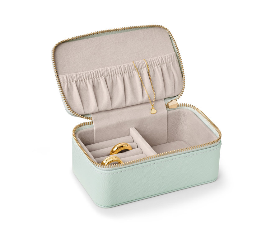 Geöffnete kleine Schmuckdose in Hellgrün mit goldenen Ringen und Halskette.