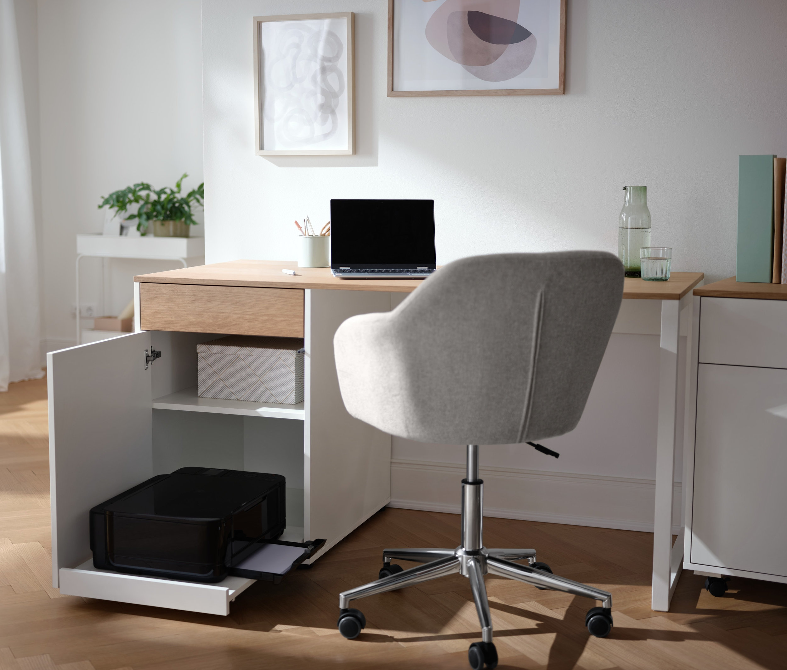 Schreibtisch mit Stauraum mit Laptop, Drucker und Büromaterialien.