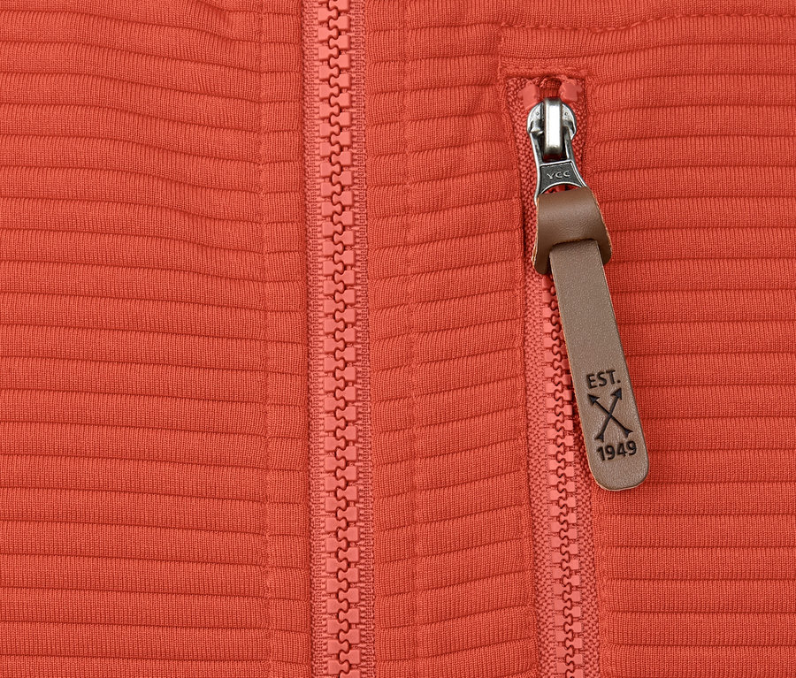 Detailaufnahme einer orangefarbenen Funktionsjacke mit Reissverschluss und Tasche.