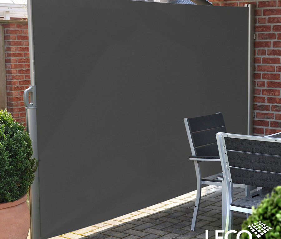 Graue Leco Seitenmarkise, 180 x 300 cm, neben einer Ziegelmauer und Gartenmöbeln.