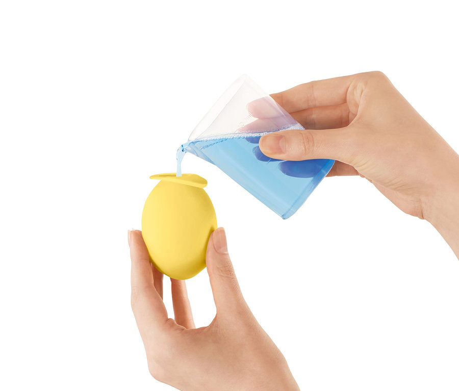 Frau gießt Flüssigkeit aus einem Messbecher in einen gelben Wasserhahn-Entkalker-Aufsatz.