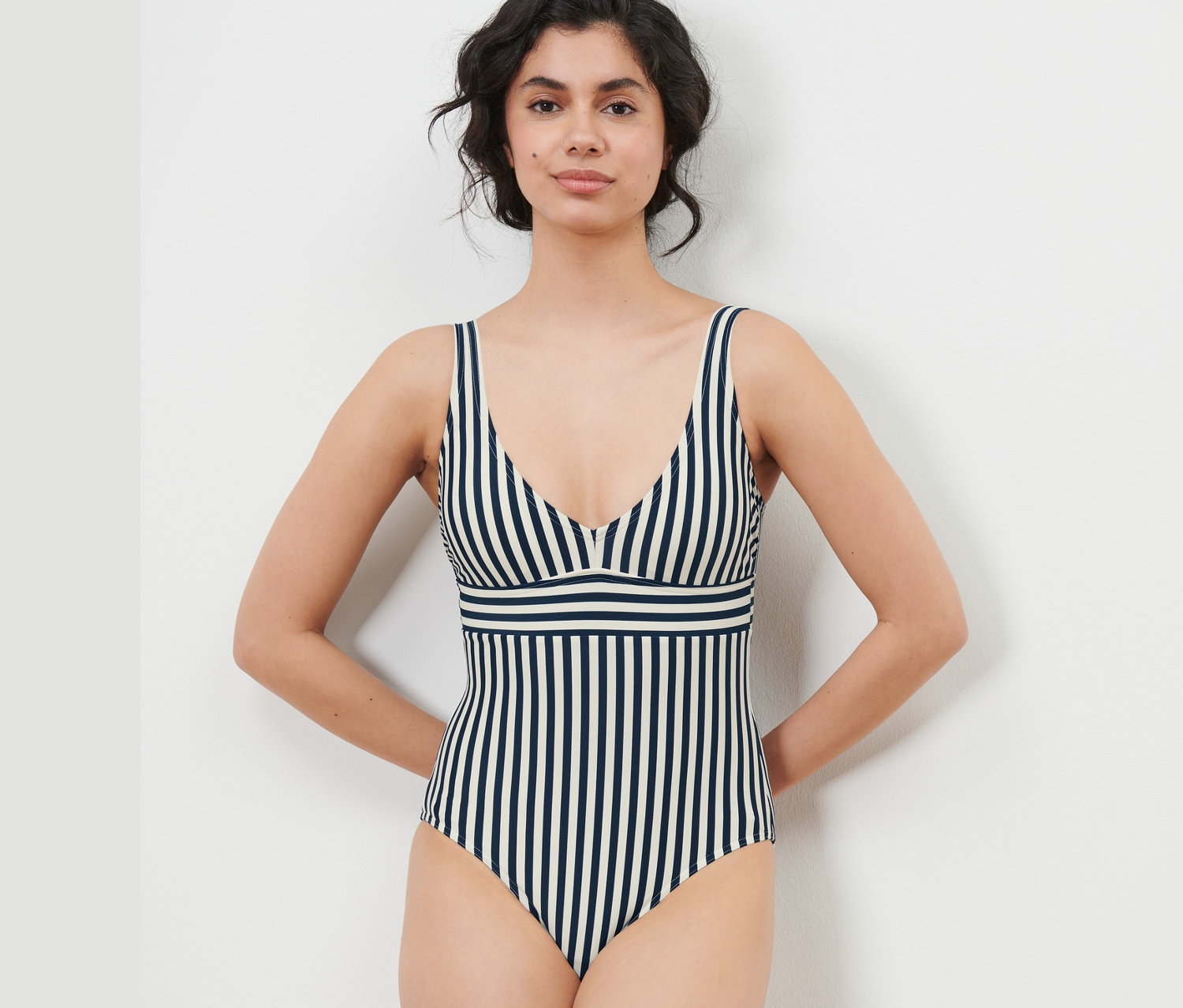 Frau posiert in einem blau-weiß gestreiften Badeanzug.