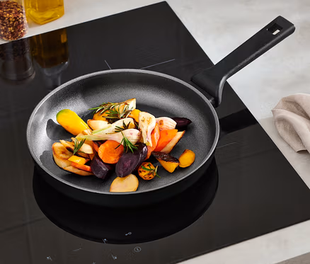 Gemüse wird in einer ca. 24 cm großen Profi-Aluminium-Pfanne gebraten.
