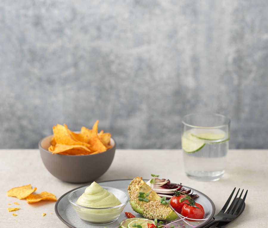 Teller mit Avocado, Tomaten, Limette und Dip neben einer Schüssel mit Chips und einem Glas Wasser. ISI Creative Whip, 0,5 l