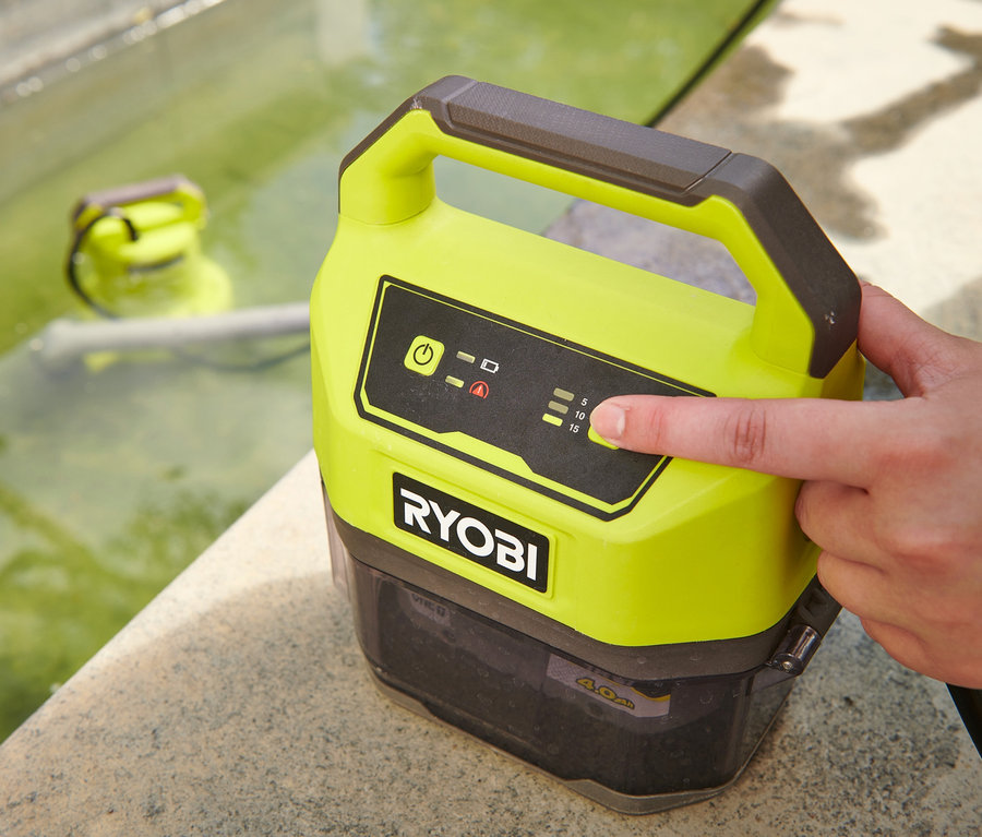 Eine Hand schaltet eine gelb-schwarze RYOBI 18 V One+ Akku-Tauchpumpe ohne Akku und Ladegerät mit einem Finger ein, eine zweite Pumpe liegt im Wasser.
