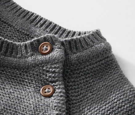 Detailaufnahme eines Kinder-Strickpullovers mit braunen Knöpfen.