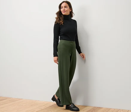 Frau trägt schwarzen Rollkragenpullover und Jerseyhose.