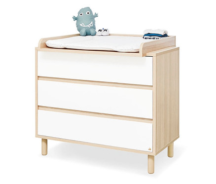 Kommode mit Wickelaufsatz, darauf ein blaues Stofftier, Schuhe und gefaltete Kleidung.