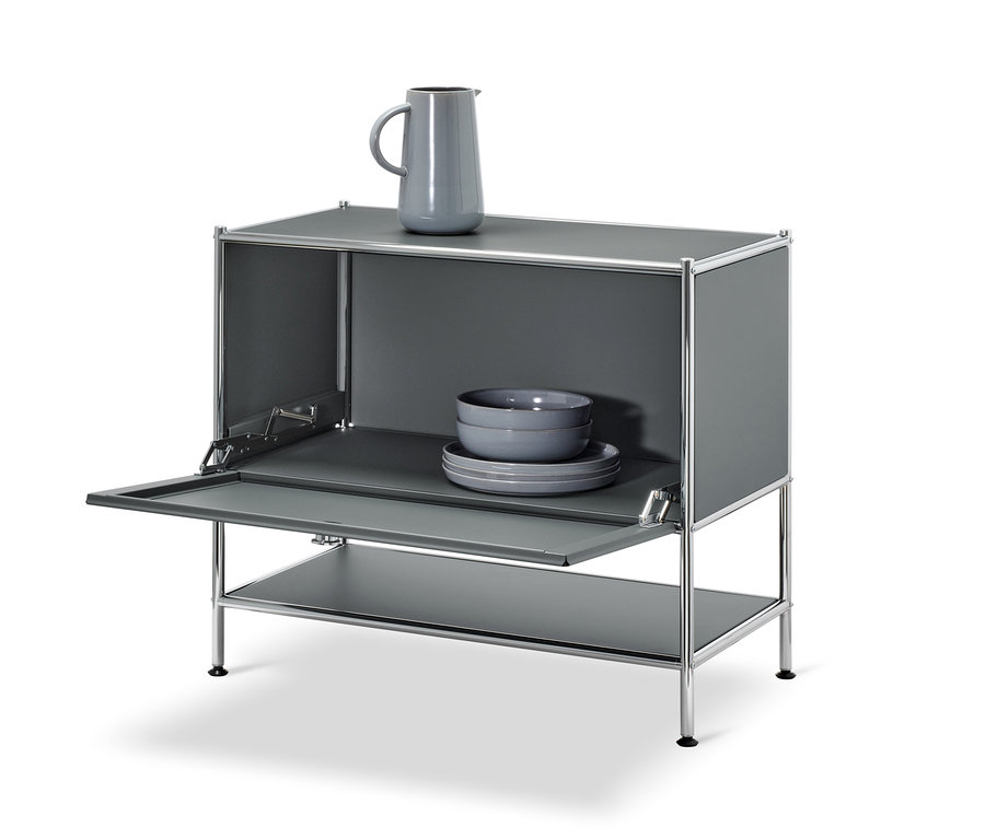 Graues Sideboard »CN3« mit geöffneter Klappe. Auf dem Sideboard stehen eine graue Vase, darin graue Schalen und Teller.