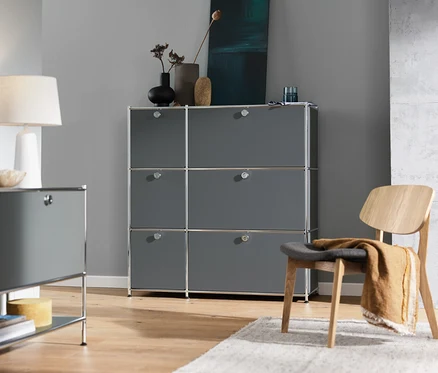 Innenaufnahme mit grauer Kommode »CN3« mit 6 Klappen, grauem Sideboard »CN3« mit 1 Klappe, weißer Tischleuchte und Loungechair.