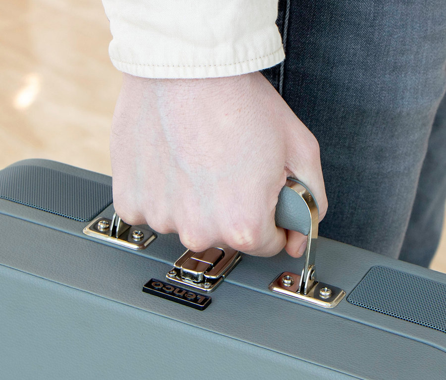 Hand hält grauen Lenco TT-116 Plattenspieler in Kofferform.