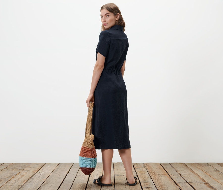 Frau blickt über die Schulter und trägt ein Hemdblusenkleid.