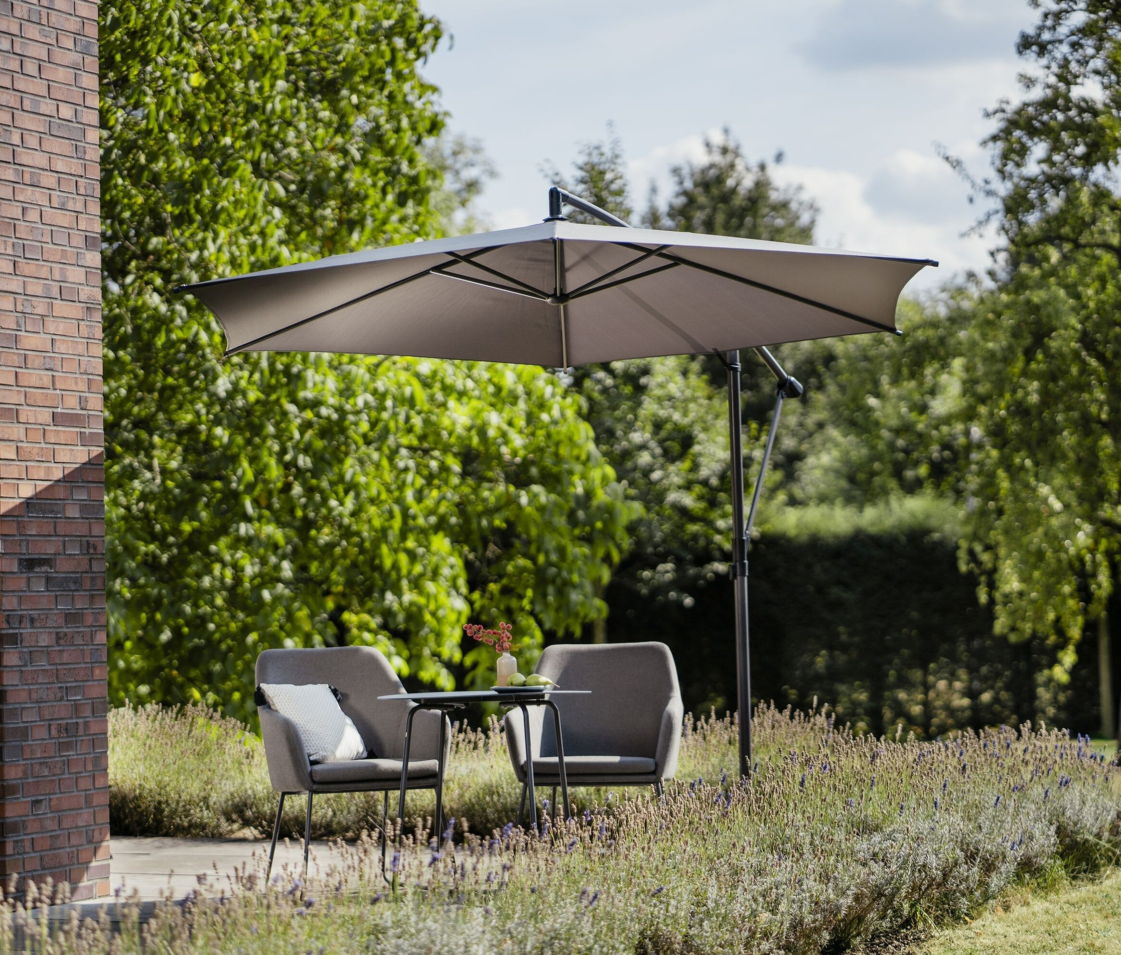 Zwei graue Sessel und ein Tisch stehen unter einem grauen Leco Ampelschirm* Ø 300 cm, inkl. Schirmständer und Abdeckhaube.