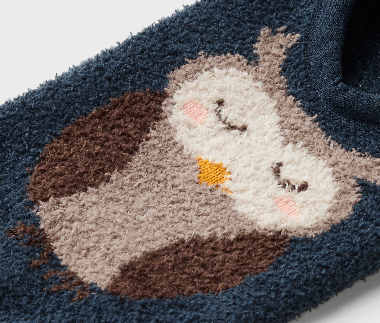 Detailaufnahme einer blauen Socke mit Cartoon-Eulenmotiv.