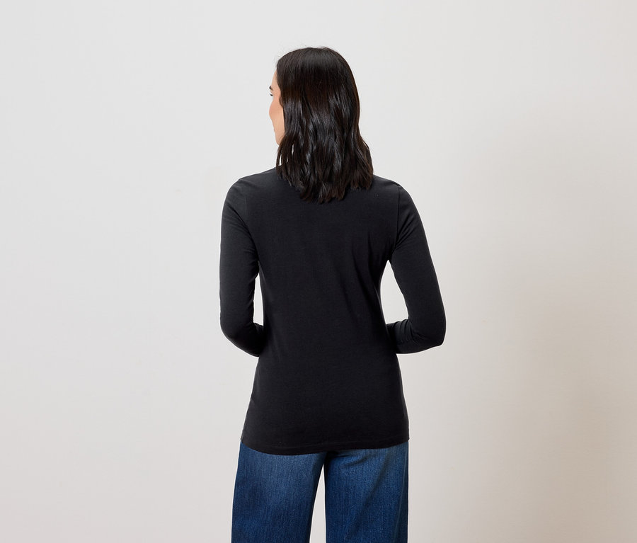 Frau mit dem Rücken zur Kamera trägt ein schwarzes Langarmshirt und blaue Jeans.