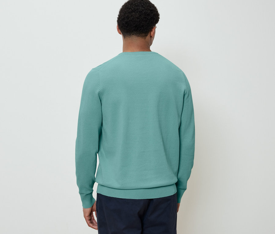 Mann von hinten trägt einen Strick-Pullover und eine dunkelblaue Hose.