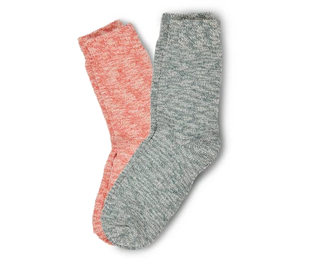 Zwei gestrickte Socken, eine aprikosenfarbene und eine blaugraue, liegen nebeneinander auf einem weißen Hintergrund.