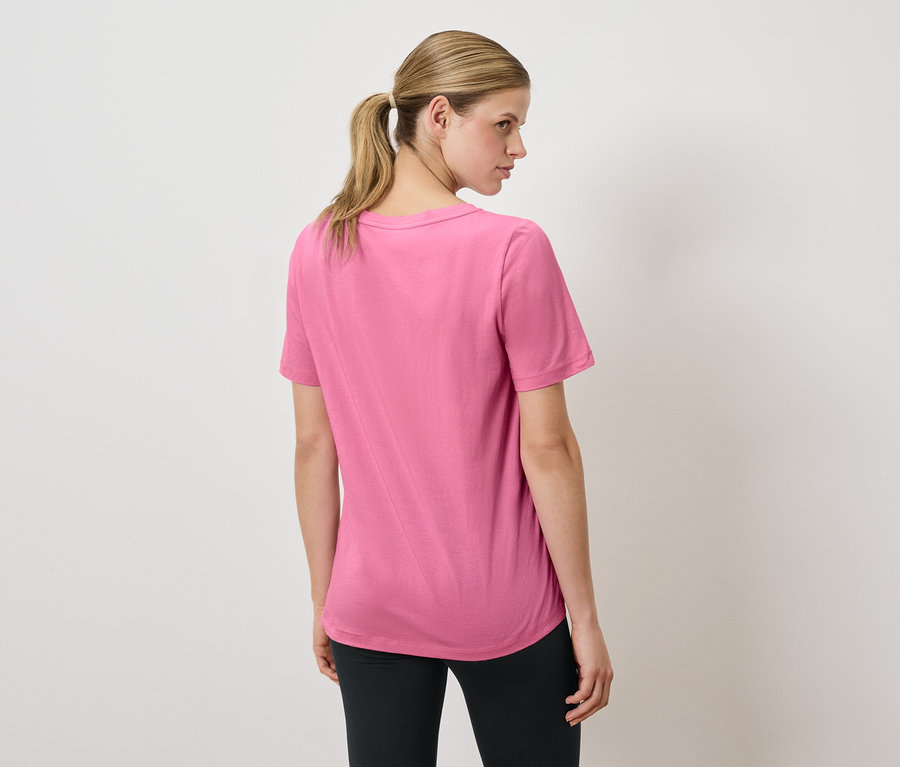 Frau trägt ein pinkes T-Shirt und schwarze Leggings.