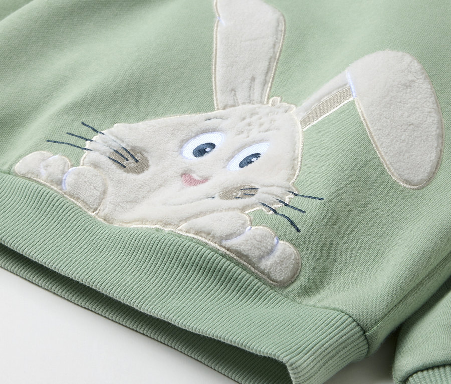 Ein hellgrünes Sweatshirt mit einem aufgenähten Hasenkopf.