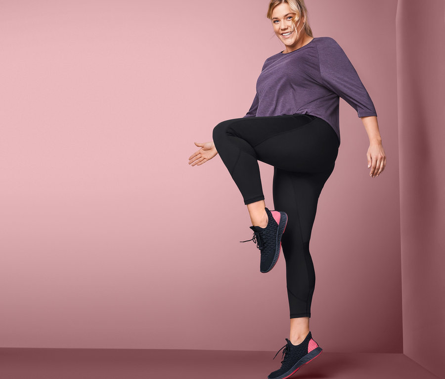 Frau posiert in Sporttights und Sportschuhen.