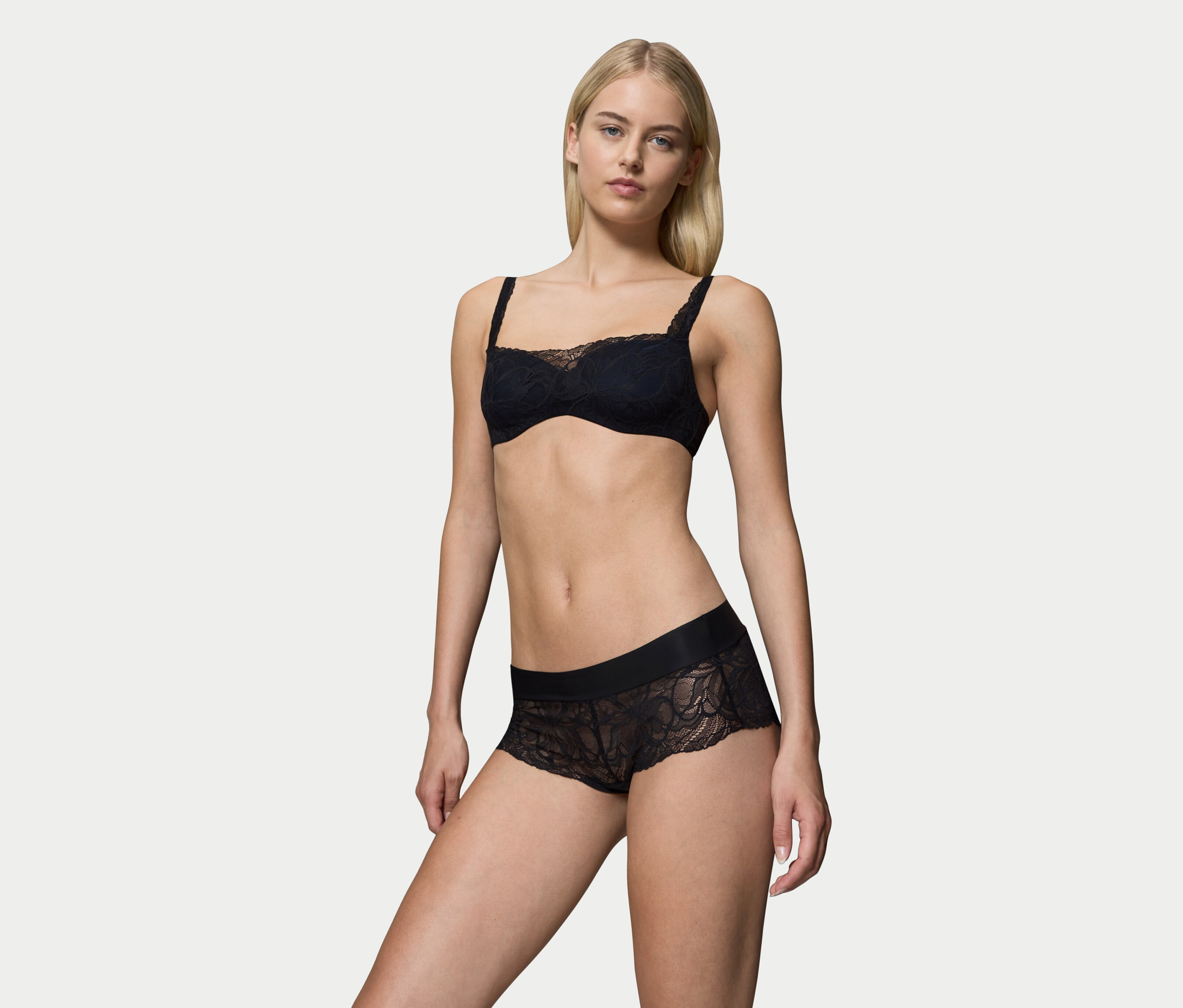 Blonde Frau posiert in schwarzem Spitzen-BH und Höschen.