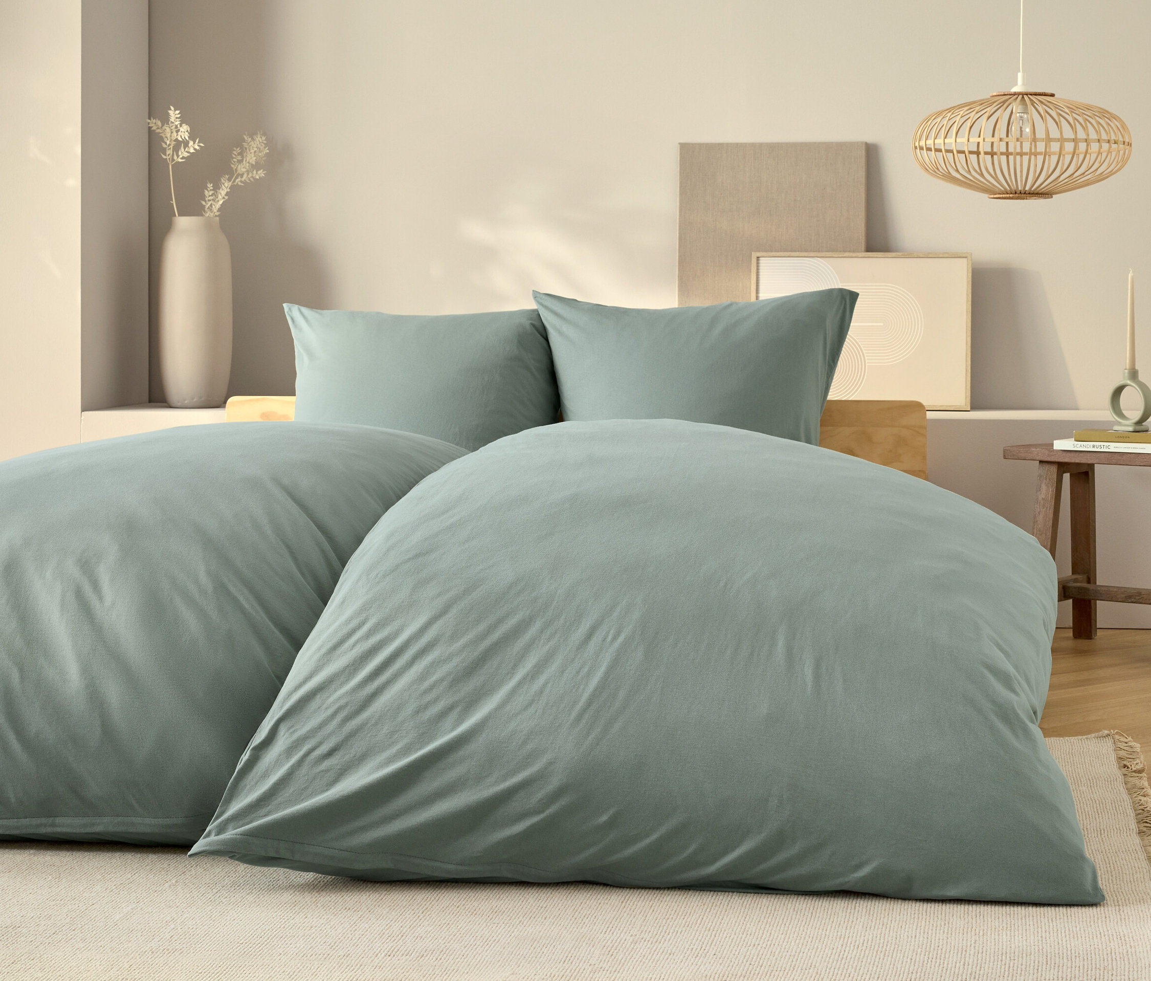 Hellblaue Bettwäsche liegt auf einem Bett mit zwei Kissen und einem hölzernen Nachttisch.