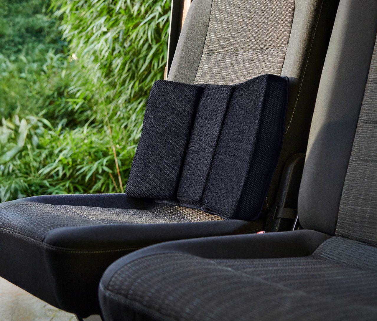 Ein schwarzes Lendenkissen befindet sich auf einem Autositz.