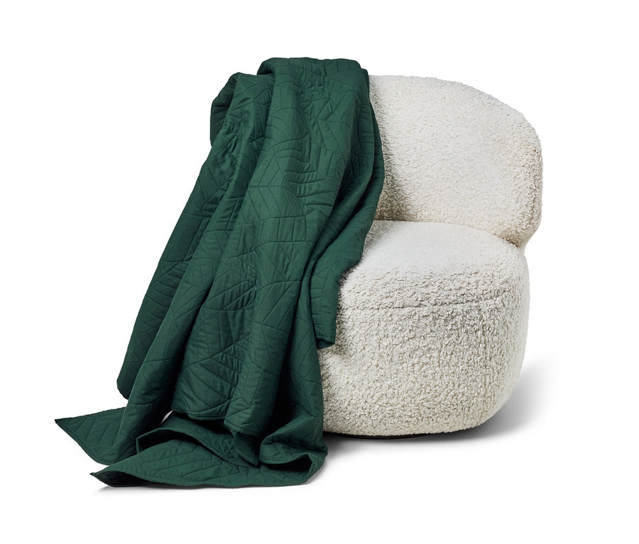 Ein dunkelgrüner, gesteppter Bettüberwurf (230 x 250 cm) liegt auf einem weißen Sessel.