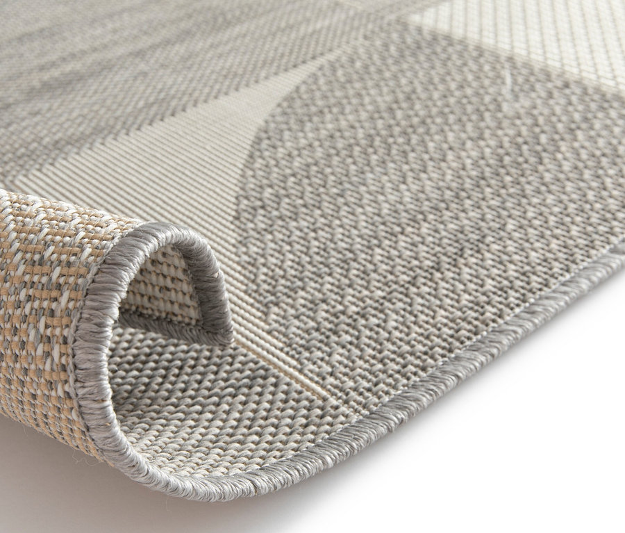 Nahaufnahme eines grau gefalteten Outdoor-Teppichs mit geometrischem Design.