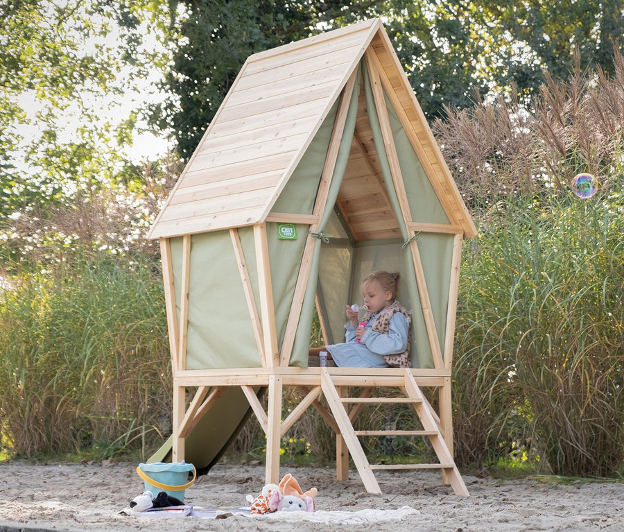 Kind sitzt im EXIT Spielhaus »Yuki 300« mit Rutsche und macht Seifenblasen.