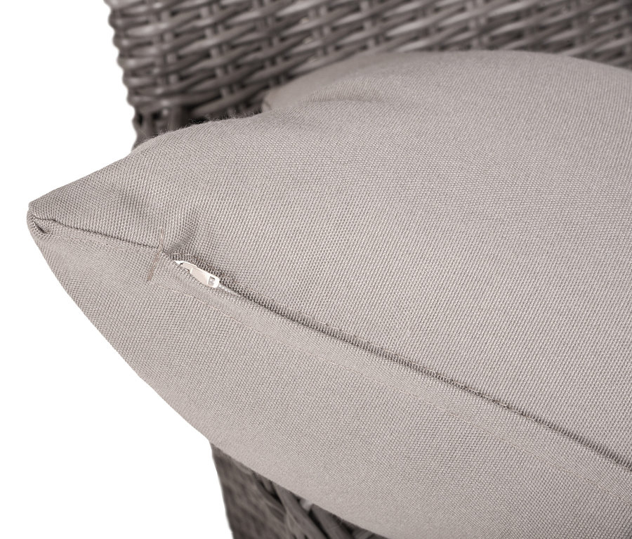 Nahaufnahme eines grauen Kissens mit Reißverschluss auf einem grauen Rattansessel.