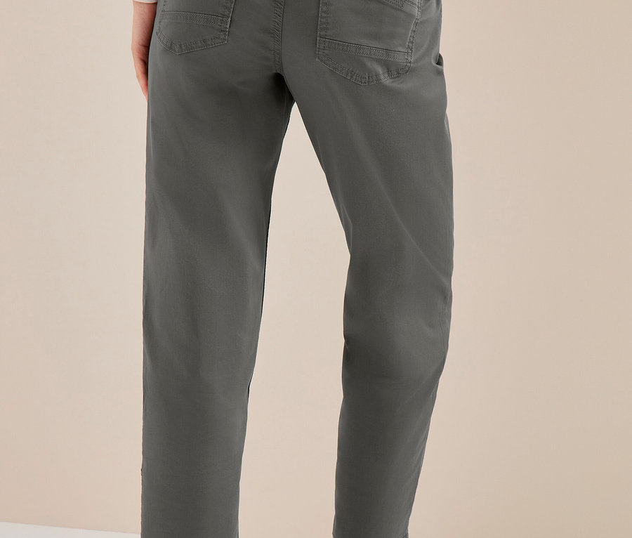 Person von hinten in dunkelgrauer CECIL Hose und silbernen Sneakers, eine Hand in der Gesäßtasche.