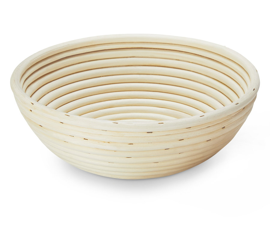Eine runde, helle Gärform aus Rattan steht auf einem weißen Untergrund.