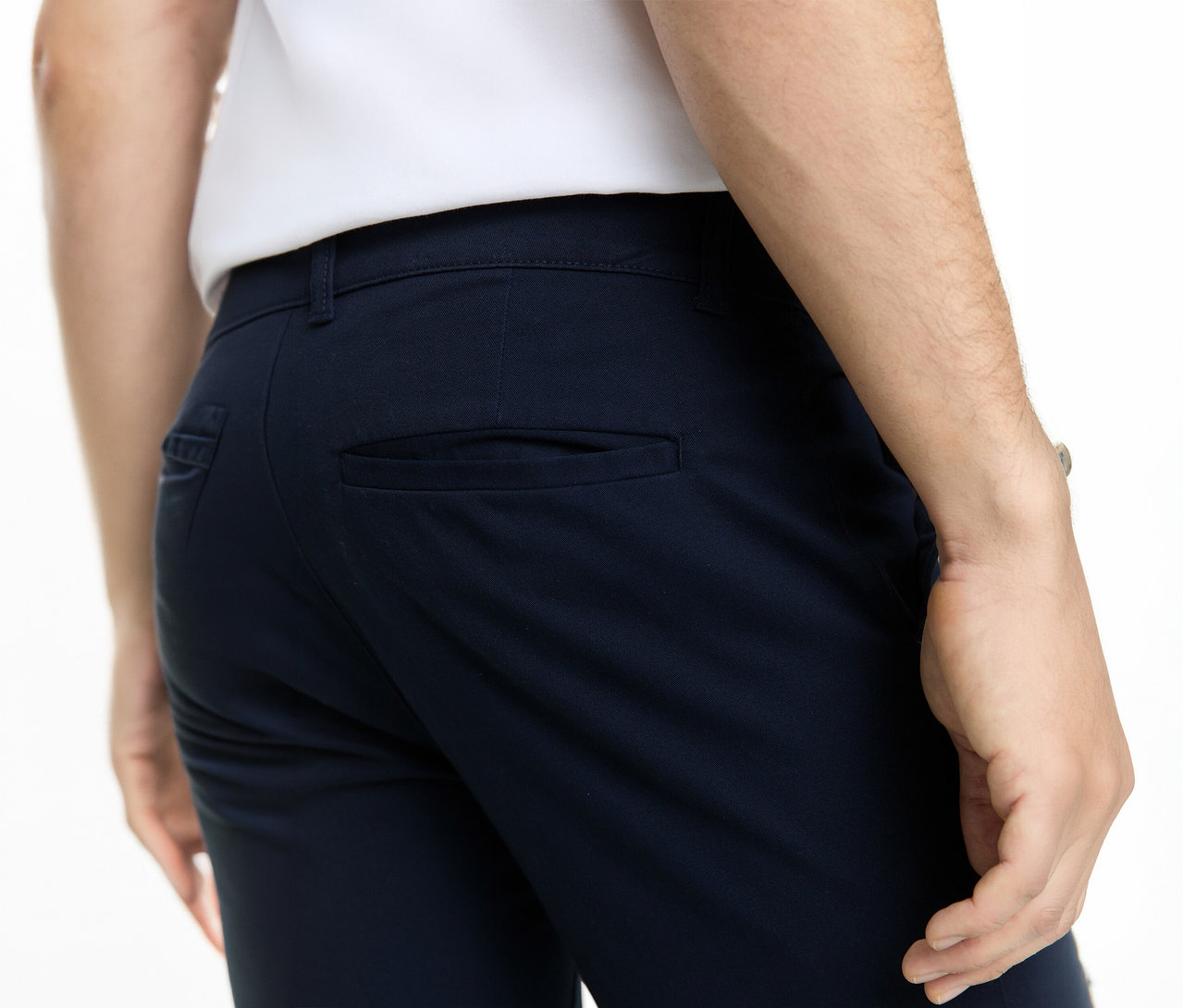 Rückenansicht einer Person in dunkelblauer Hose und weißem Hemd. Die Hose hat Gesäßtaschen.