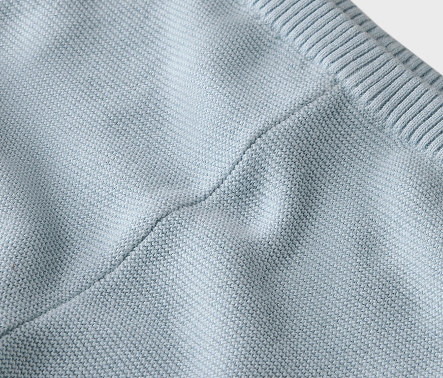Nahaufnahme eines hellblauen Strickstoffes mit Naht.