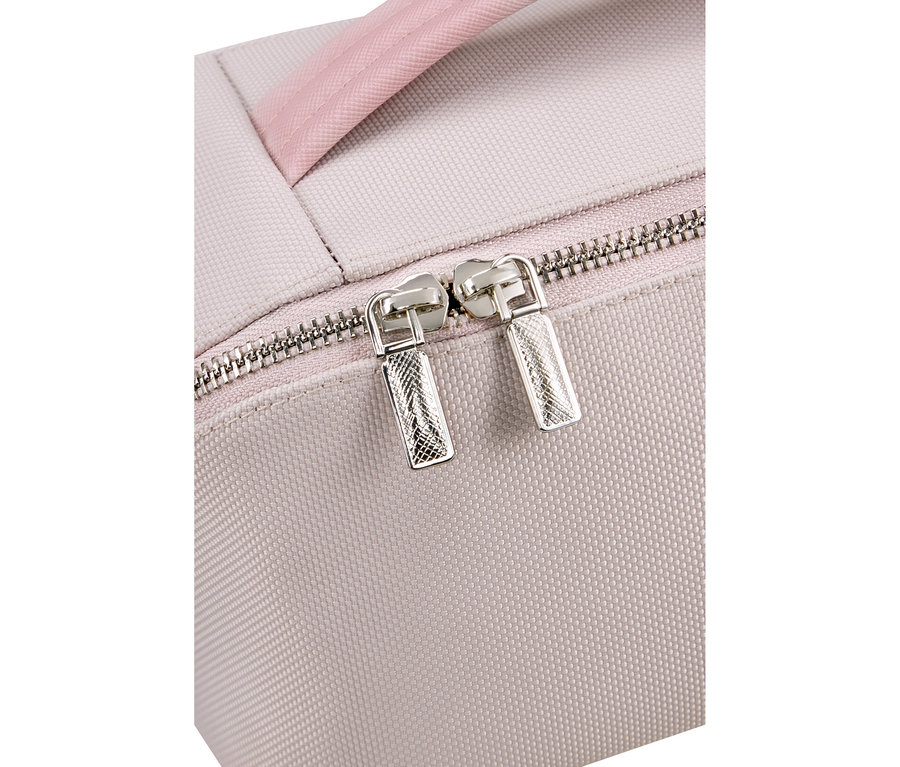 Nahaufnahme einer hellrosa gewebten Stofftasche mit einem silbernen Reißverschluss und zwei silbernen, strukturierten Reißverschlussziehern. Ein rosa Griff ist oben sichtbar.