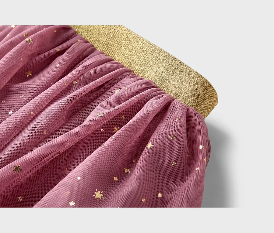 Nahaufnahme eines rosa Tüllrocks mit goldenen Glitzersternen und einem breiten, goldenen Gummibund.